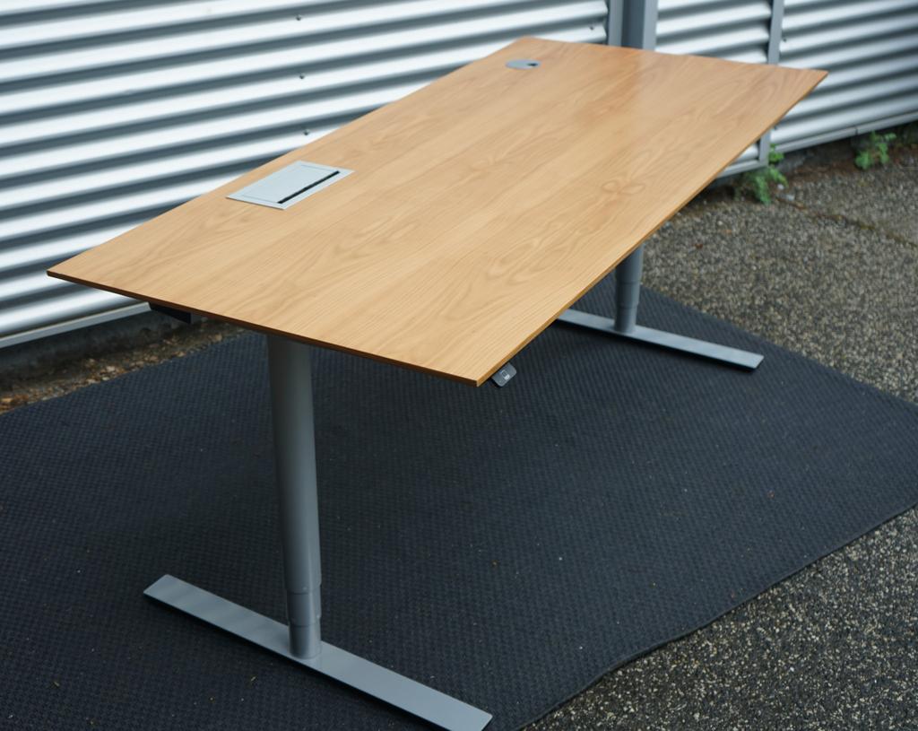 Dencon Delta hæve-sænkebord 180x80 i træfarvet finish set fra skrå vinkel.